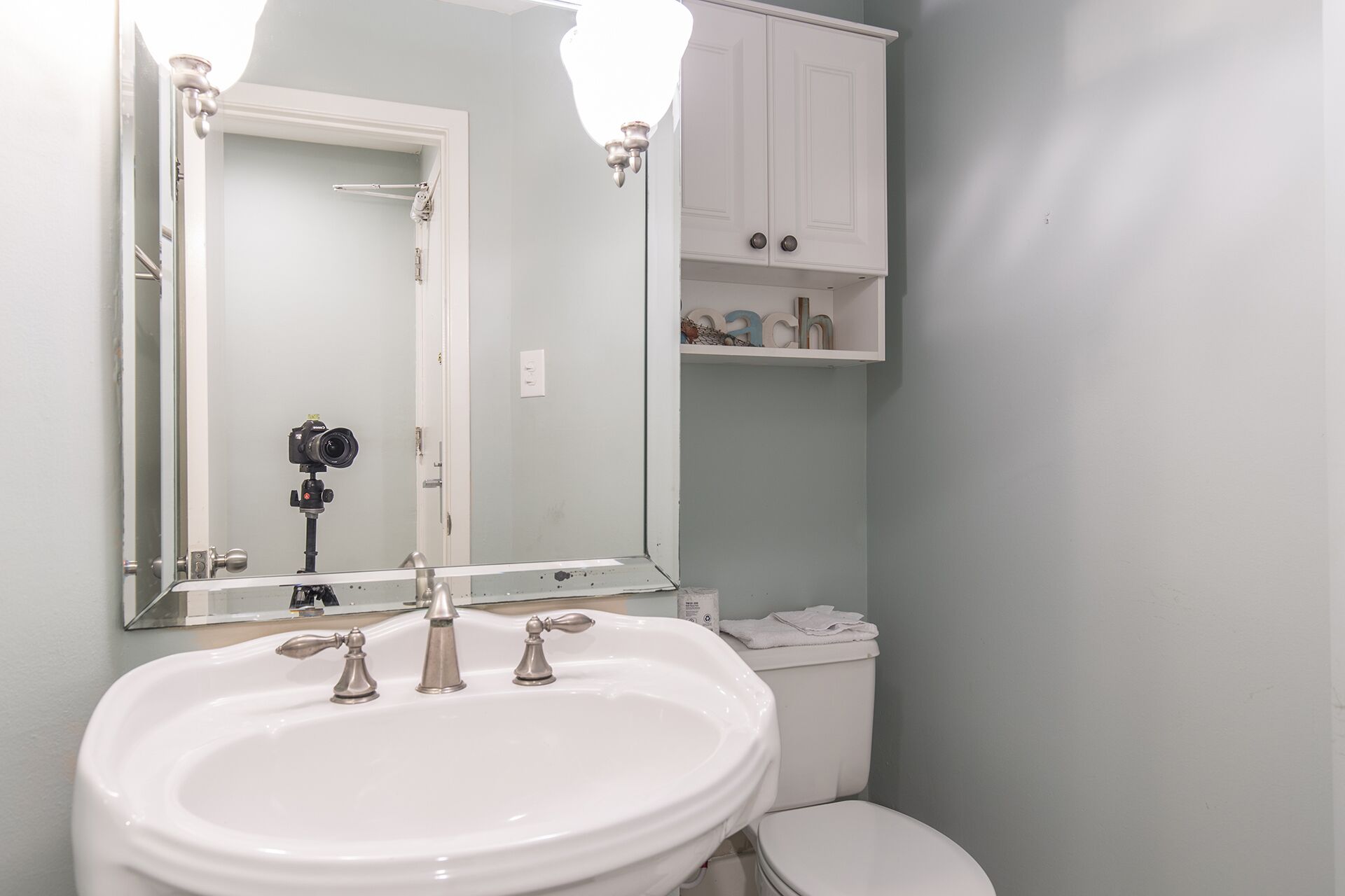 Un bany amb un mirall gran, un lavabo blanc i un vàter.