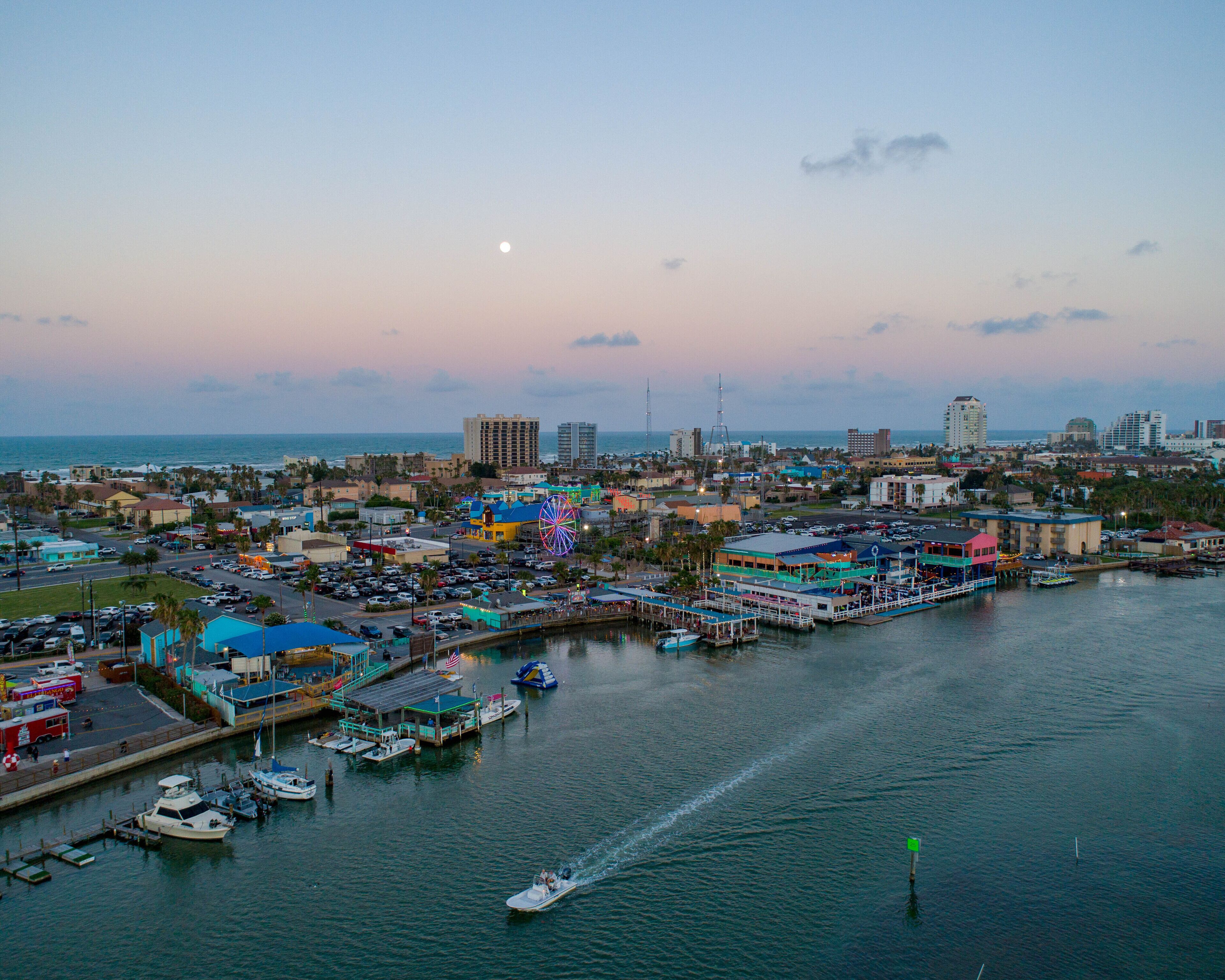 A coastal cityscape with a marina, boats, and buildings.