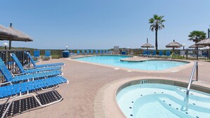 Ein Poolbereich mit Liegestühlen und Sonnenschirmen, einem Whirlpool und freiem Blick auf den Ozean.