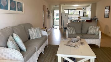 A living room with a sofa, armchairs, a coffee table, and a dining area in the background.