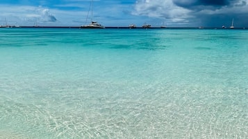 A clear turquoise sea with several boats anchored in the distance.