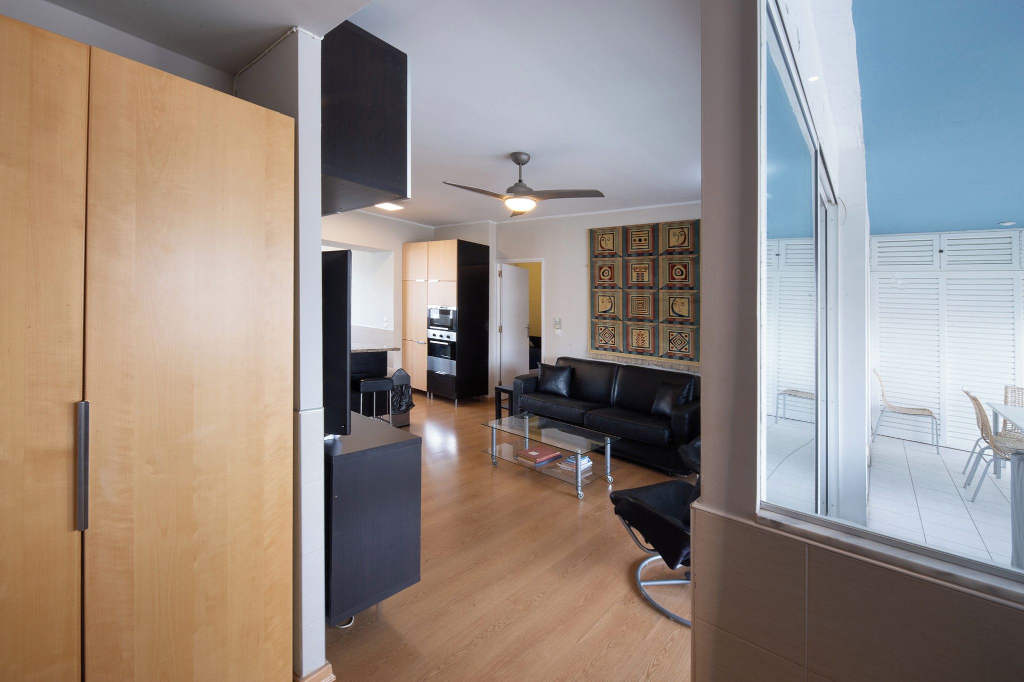 Un apartamento moderno con cocina, comedor y sala de estar con un sofá de cuero negro.