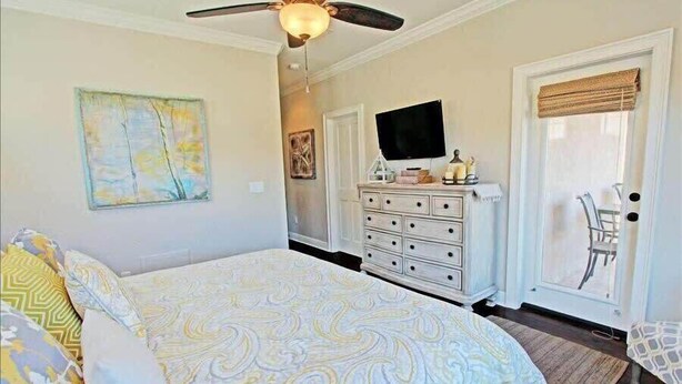 Une chambre à coucher comprenant un lit, une commode, un téléviseur et des œuvres d’art.