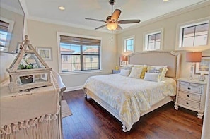 A bedroom with a large bed, a ceiling fan, and a nightstand with a lamp.