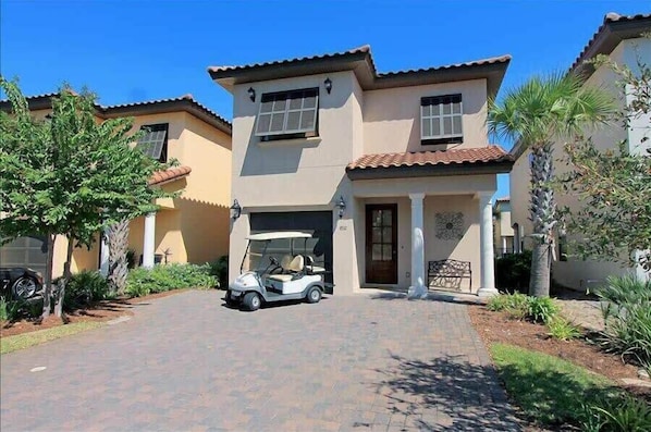 A two-story house with a driveway, a golf cart, and a well-maintained garden.