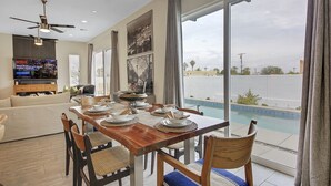 A dining area with a view of a swimming pool, a television, and a ceiling fan.