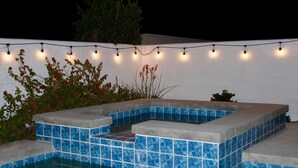 A swimming pool with blue-tiled steps and a white wall in the background.