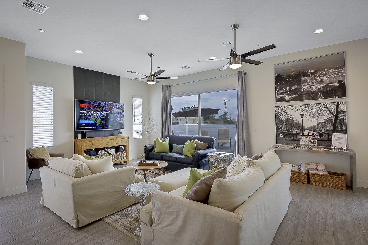 A modern living room with a flat-screen TV, two sofas, a coffee table, and a ceiling fan.