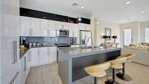 A modern kitchen with white cabinets, stainless steel appliances, and a central island with bar stools.