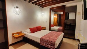 A hotel room with a bed, bedside tables, and a mirror. - Hotel Rio Piedras (Jericó)