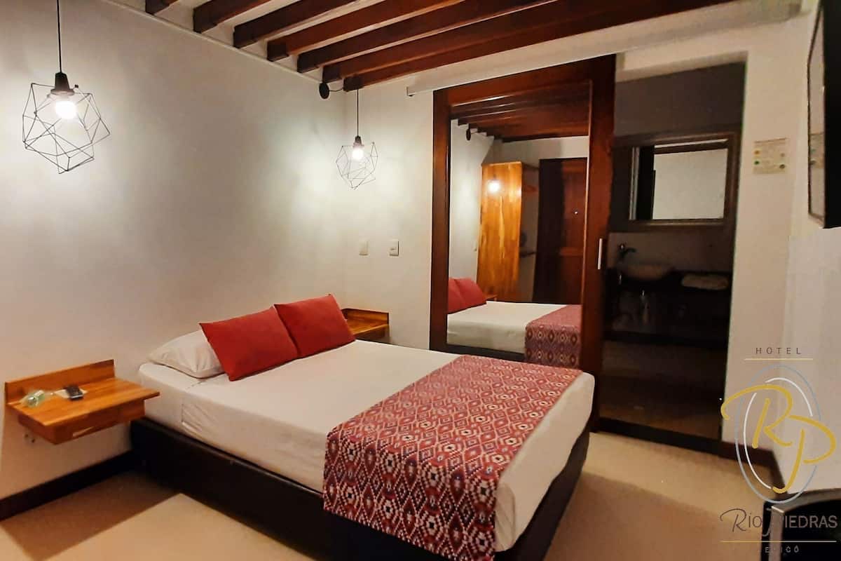 A hotel room with a bed, bedside tables, and a mirror.