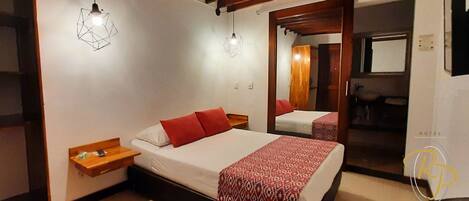 A hotel room with a bed, bedside tables, and a mirror.