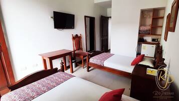 Une chambre d’hôtel avec deux lits, un bureau, une chaise, une télévision et une armoire.