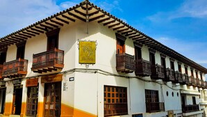 A traditional building with a balcony, a sign with a letter 'R', and a sign for 'Hotel'. - Hotel Rio Piedras (Jericó)