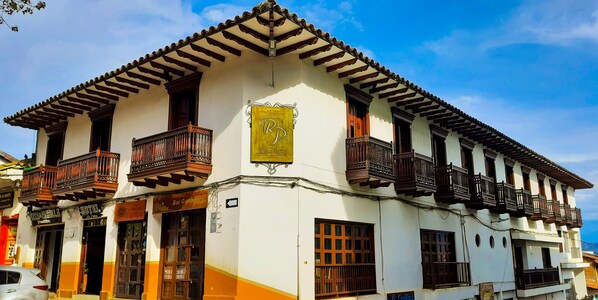 A traditional building with a balcony, a sign with a letter 'R', and a sign for 'Hotel'. - Hotel Rio Piedras (Jericó)