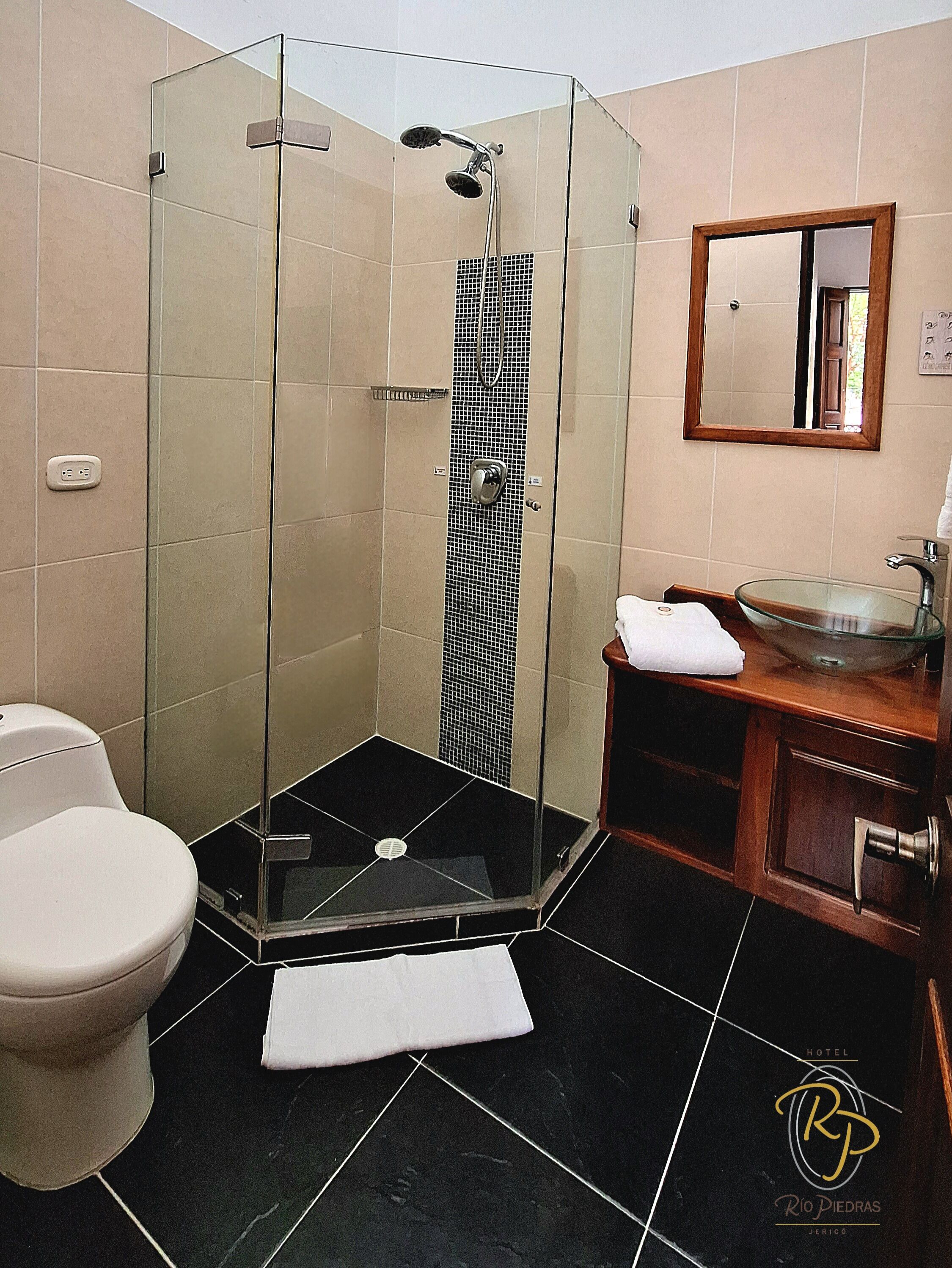 A bathroom with a glass-enclosed shower, a toilet, a sink with a glass basin, and a mirror on the wall.