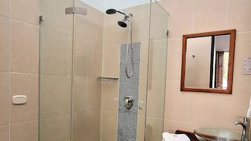 Un bagno con doccia vetrata, un water, un lavandino con lavabo in vetro e uno specchio a parete.