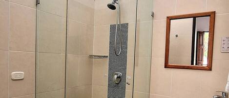 A bathroom with a glass-enclosed shower, a toilet, a sink with a glass basin, and a mirror on the wall.