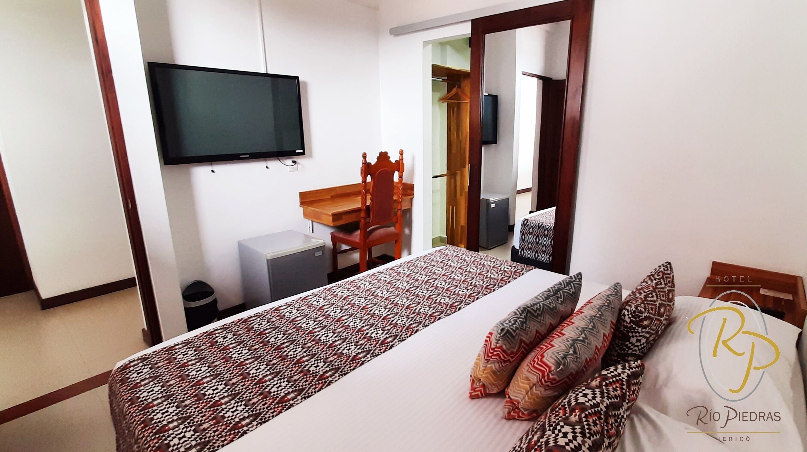 Ein Hotelzimmer mit Bett, Schreibtisch, Stuhl, Fernseher und Kleiderschrank.