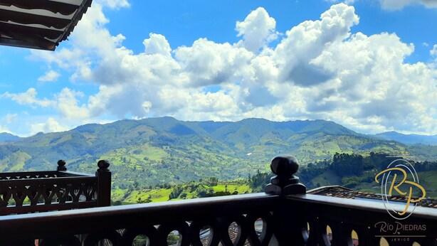 A balcony with a view of green hills and mountains under a partly cloudy sky. - Hotel Rio Piedras (Jericó)