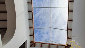 A modern hotel interior with a spiral staircase, a large window with a view of the sky, and a logo for 'Rio Piedras Hotel'. - Hotel Rio Piedras (Jericó)