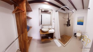 A bathroom with a wooden vanity, a large mirror, a shower, and a toilet. - Hotel Rio Piedras (Jericó)