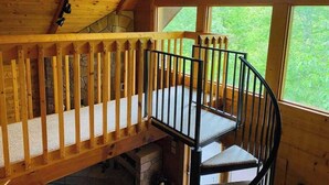 A wooden staircase with a black railing leading to a balcony.