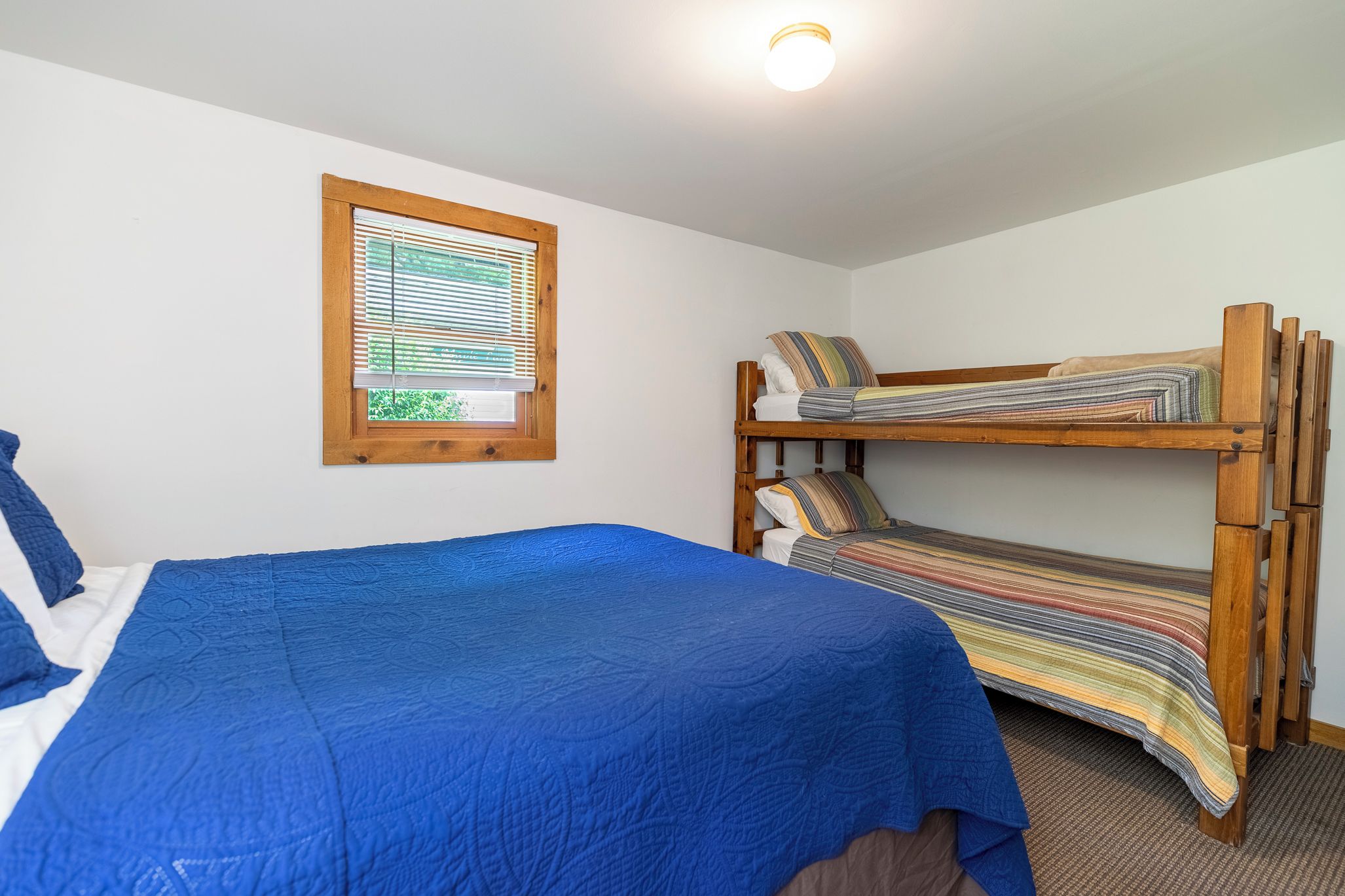 Une chambre avec un lit superposé et un lit simple, tous deux dotés de draps à rayures.