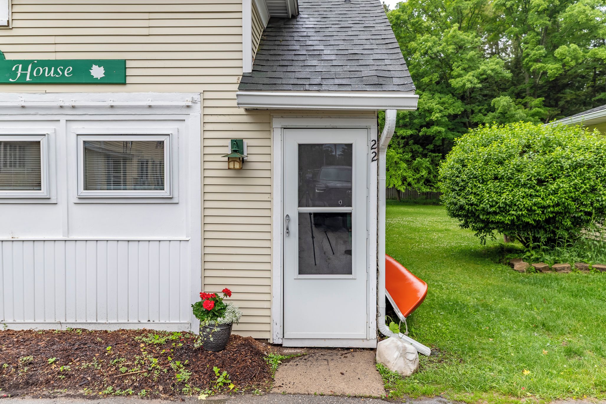 A residential house with a garage, a front door, and a small garden area with a potted plant.