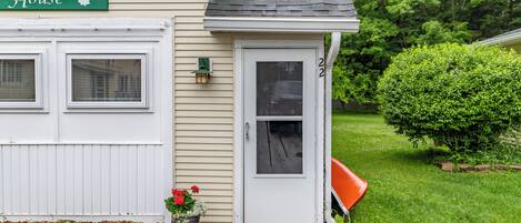 A residential house with a garage, a front door, and a small garden area with a potted plant.