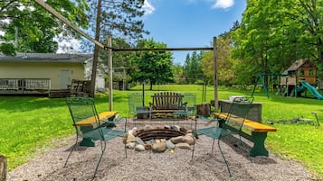 Un espace aménagé avec un foyer, des bancs et une pergola, situé dans un parc.