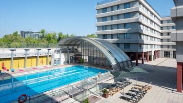 Una piscina cubierta, una piscina al aire libre de temporada, sombrillas