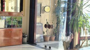 A reception area with a wooden cabinet, potted plants, and a glass door leading to the outside. - Kadikoy Rihtim Hotel (Istanbul)