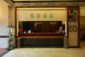 A reception area with a counter, clocks, and framed pictures on the wall. - Kadikoy Rihtim Hotel (Istanbul)