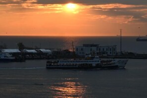 Un ferry al atardecer con vistas al agua y edificios lejanos.
