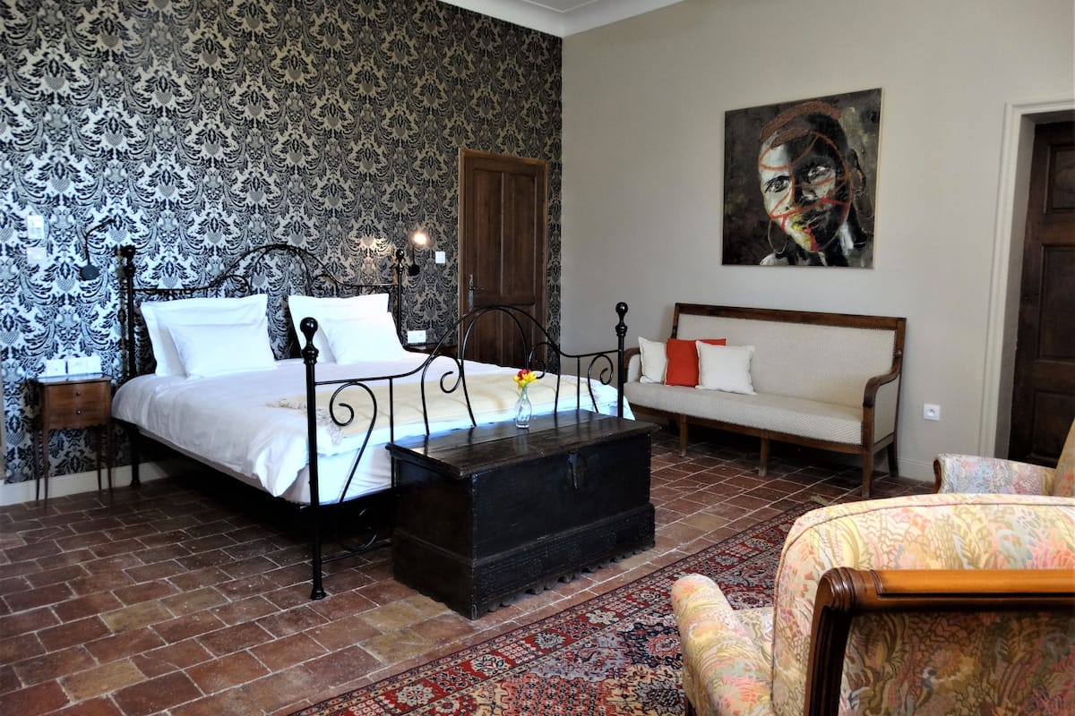 Ein Schlafzimmer mit einem Bett, einer Holzkiste, einer Couch und einem Sessel.
