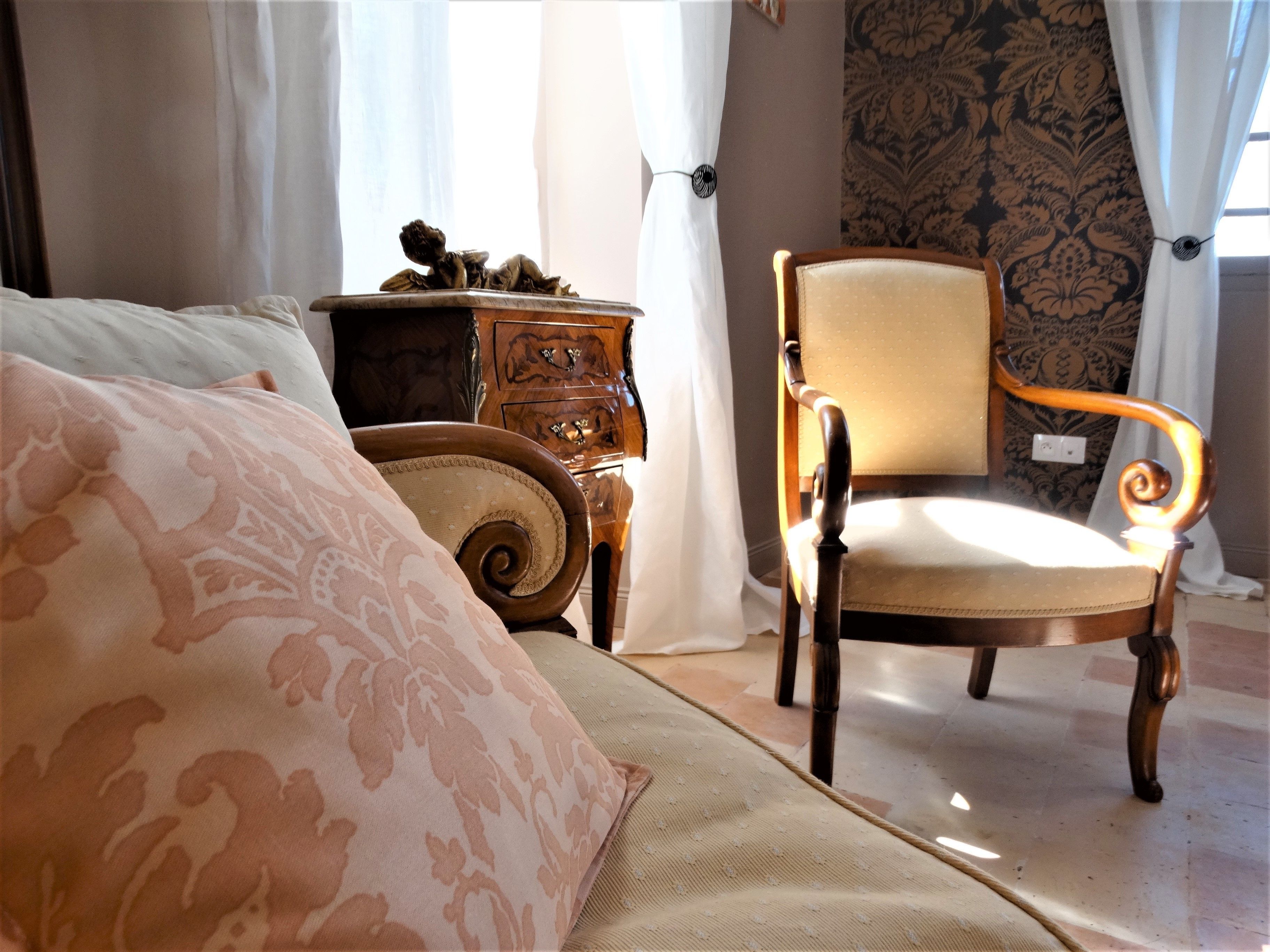 A bedroom with a bed, a chair, a nightstand, and a patterned wall.