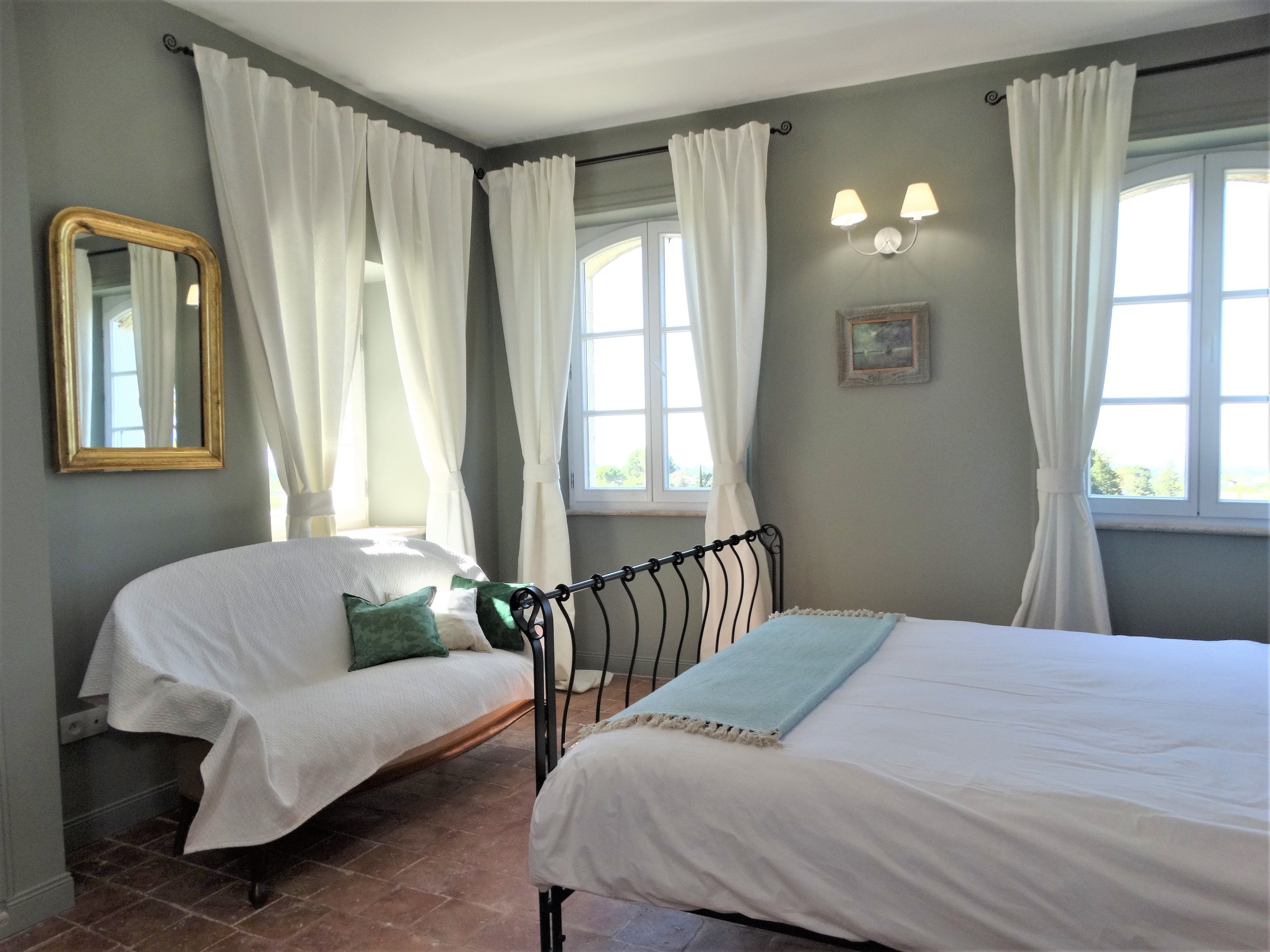 A bedroom with two beds, white bedding, a mirror, and a window with curtains.
