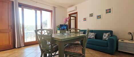 Un comedor con mesa, sillas, televisor y sofá.