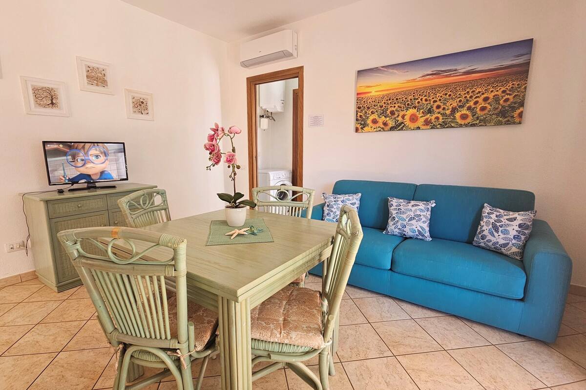A dining area with a table, chairs, a television, and a sofa.