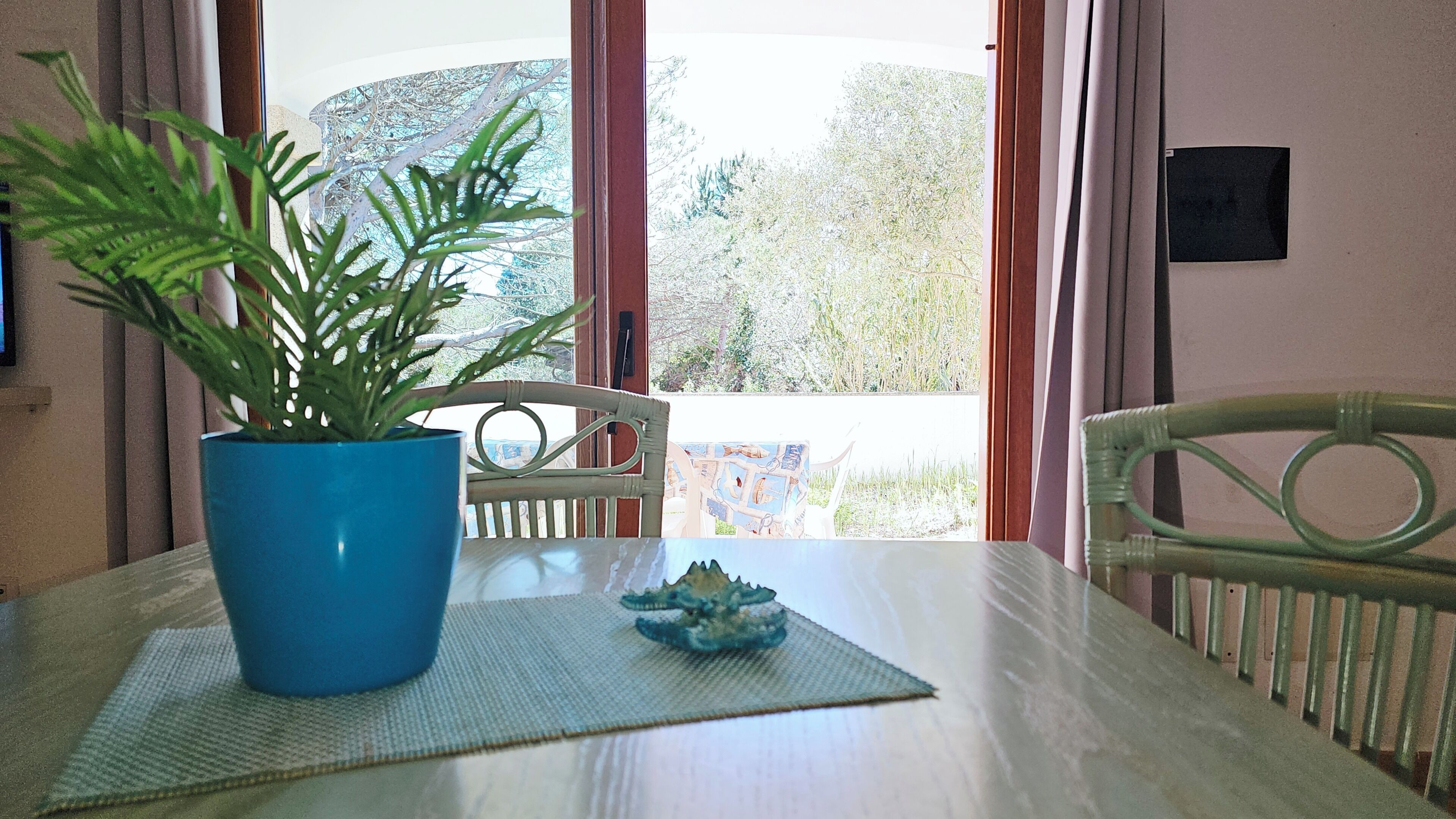Uma mesa de jantar com uma planta em vaso, um objeto decorativo e uma cadeira.
