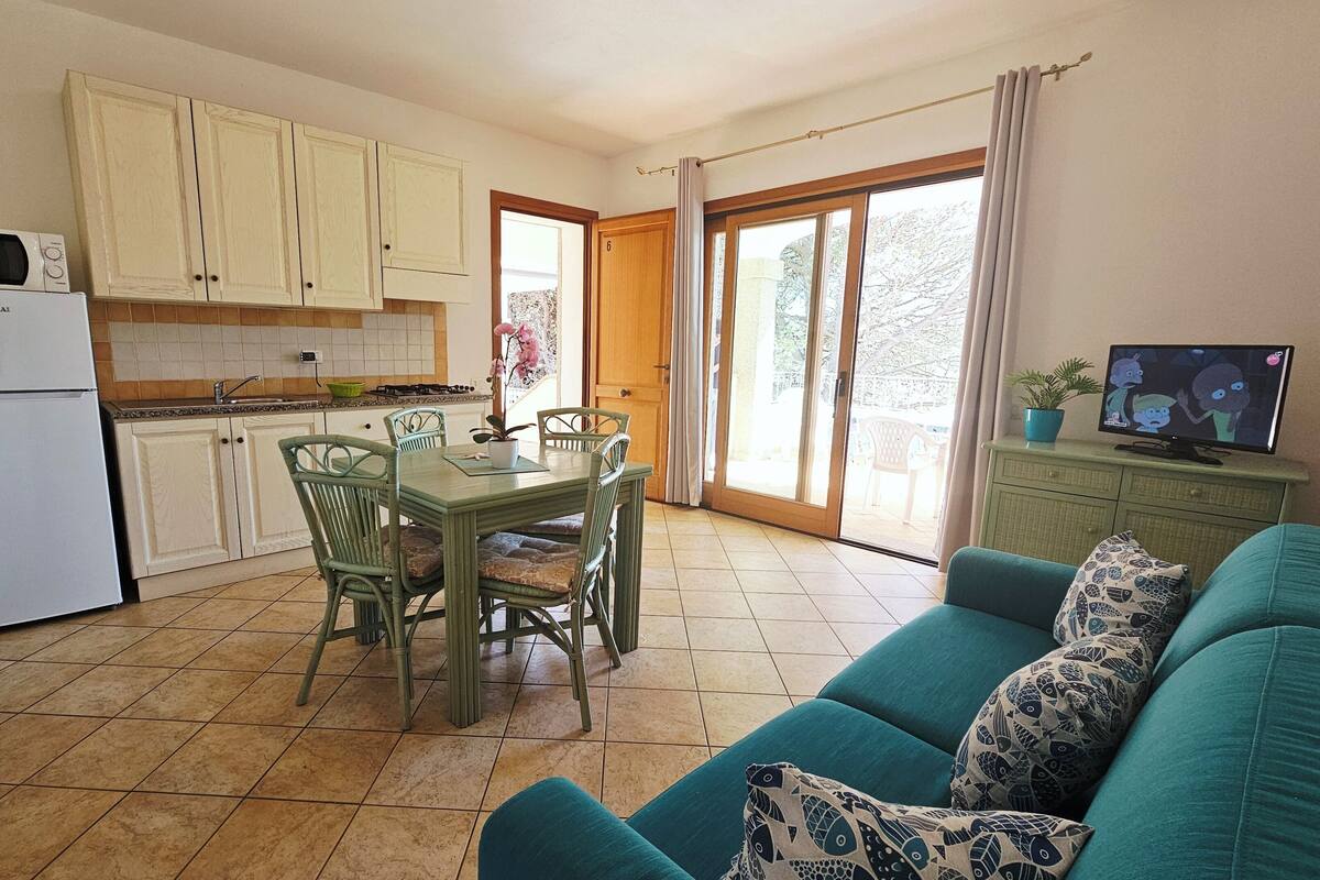 A compact living space with a kitchen, dining area, and a sofa with patterned cushions.