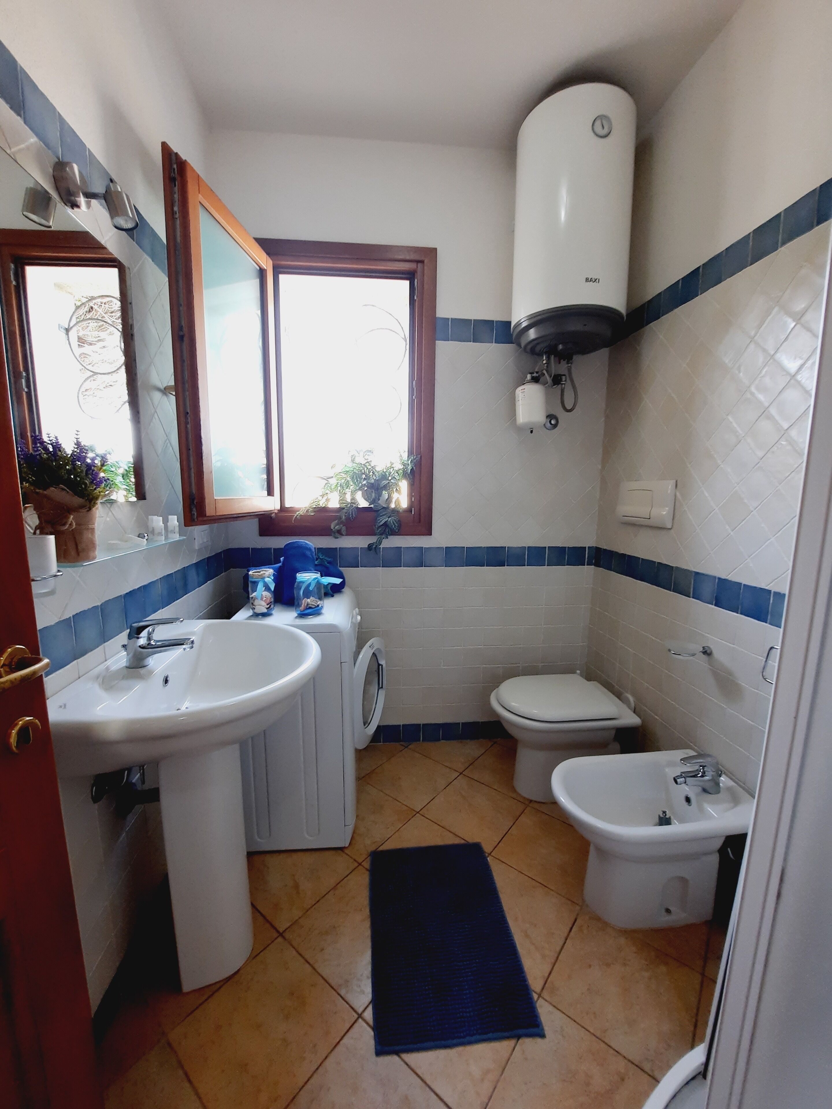 Een kleine badkamer met een wastafel, toilet, bidet en een wasmachine.