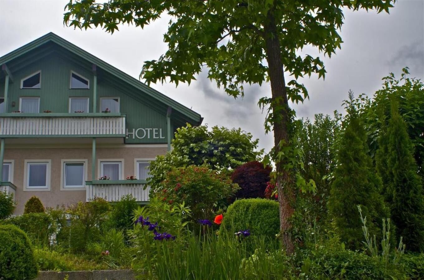 A two-story hotel with a green facade and a balcony on the upper floor.