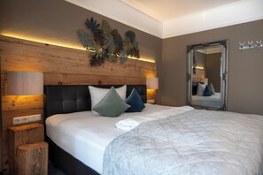 Una cama bien tendida con cubrecolcha acolchado, dos lámparas de noche y un cabecero de madera.