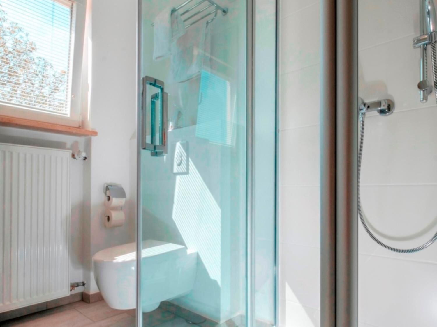 Un baño moderno con cabina de ducha de vidrio, inodoro y radiador.