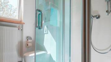 Un baño moderno con cabina de ducha de vidrio, inodoro y radiador.