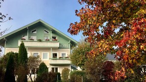 Een hotel met een groene gevel, meerdere balkons met bloembakken en een verzorgde tuin.