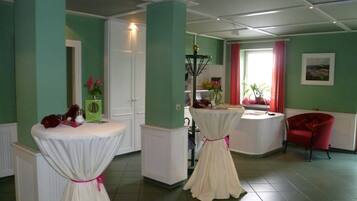 Una habitación con dos mesas blancas, una silla roja y una ventana con cortinas rojas.
