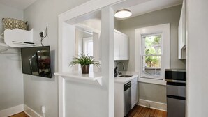 A compact kitchen with white cabinetry, a built-in dishwasher, a refrigerator, and a window providing natural light. - Fabulous Queen 1BR: 400ft to Beach! FREE PARKING + WIFI (Tybee Island)